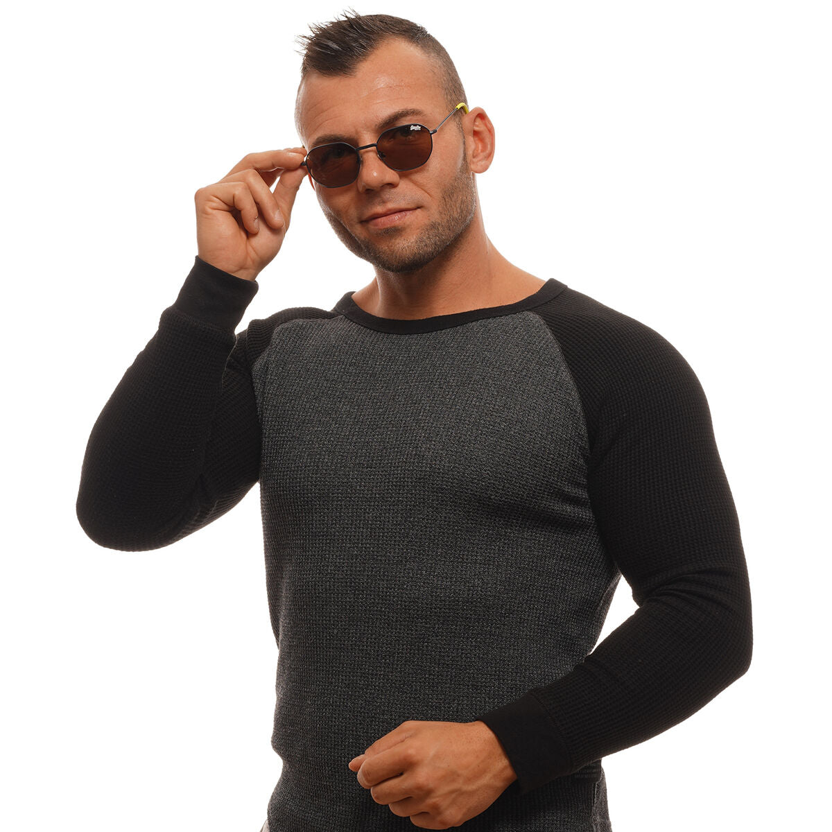 Heren in een zwart-grijze trui met Superdry zonnebril in hand, trendy uitstraling.