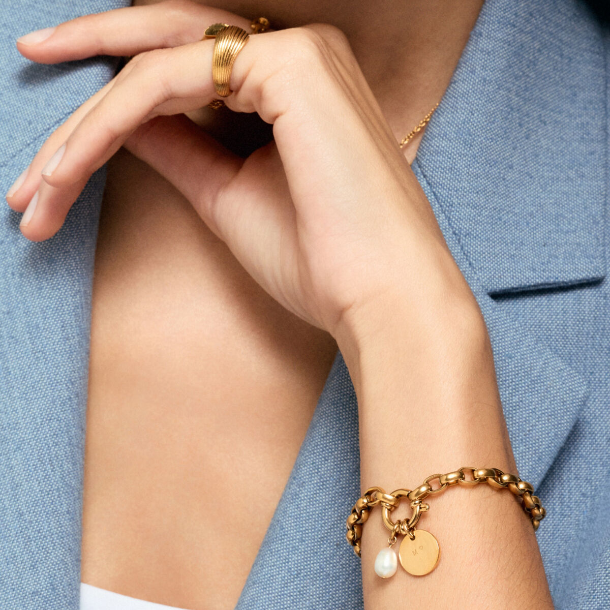 Close-up van de gouden One Jewels armband met een parel en een ronde hanger.