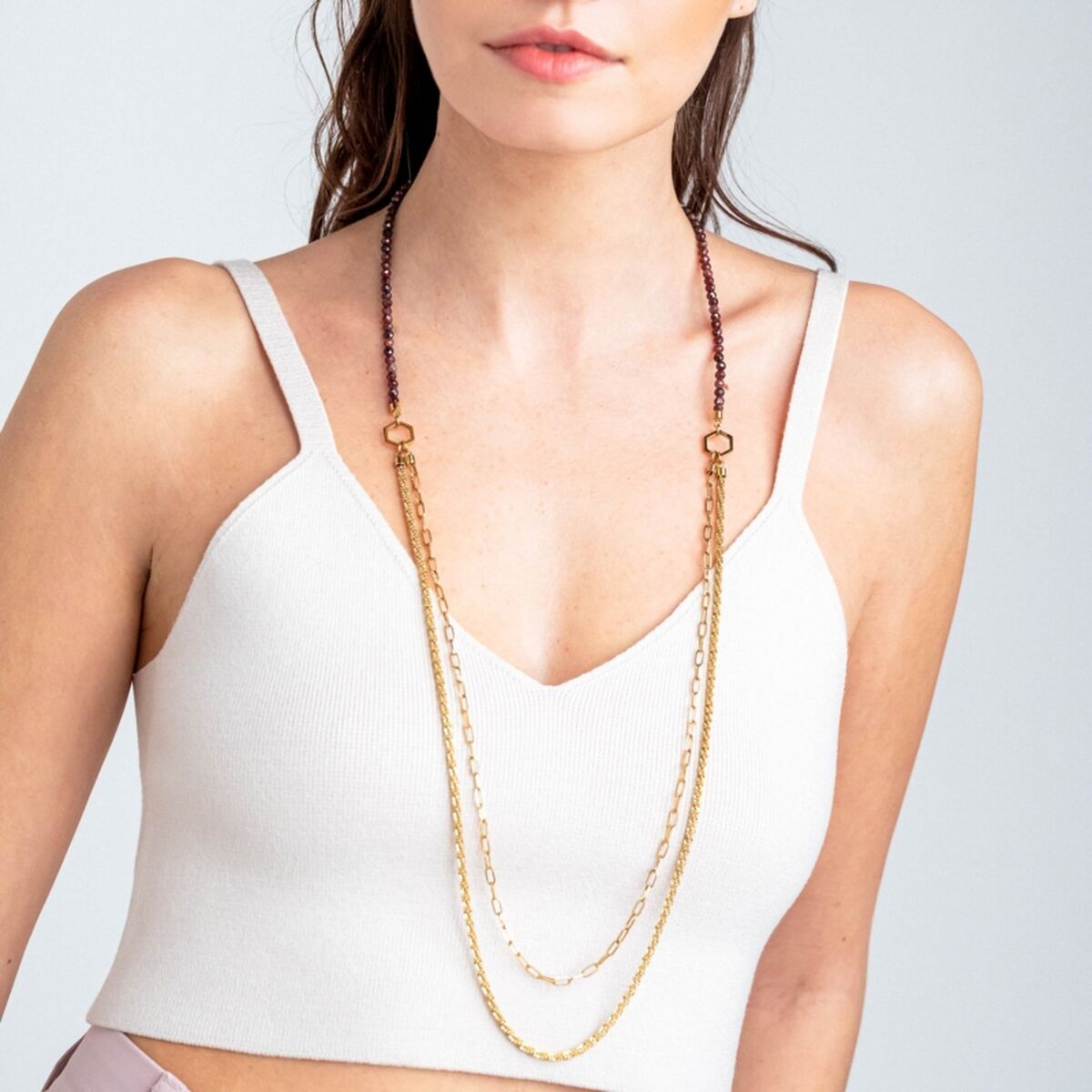 Detail van de Breil ketting met gouden en paarse schakels, gedragen door een model.