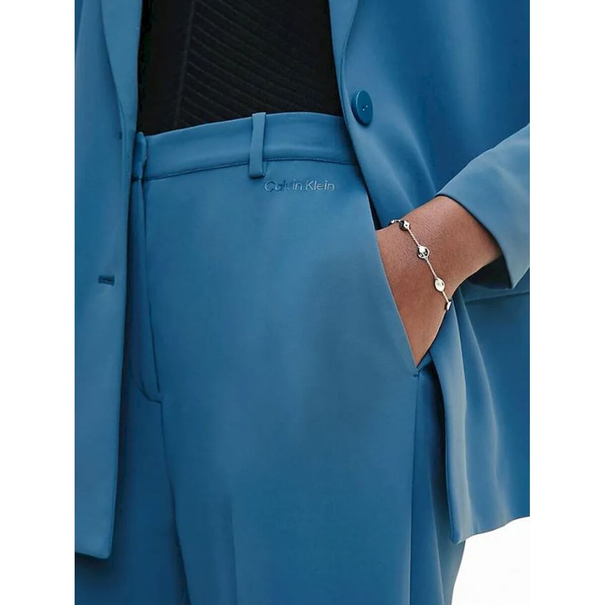 Detail van de Calvin Klein armband, elegant gedragen met een blauwe outfit.