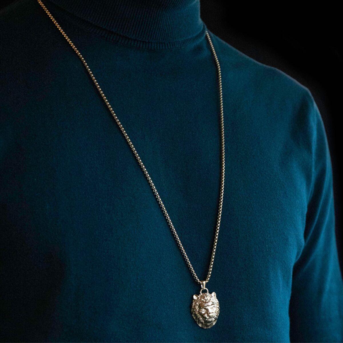 Zijaanzicht van de Guess ketting met leeuwenhanger, elegant gedragen op een donkere trui.