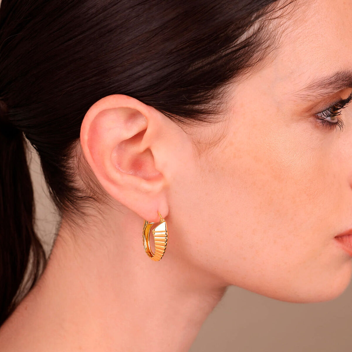 Detail van de gouden Etrusca oorbellen in elegant design, gedragen aan het oor.