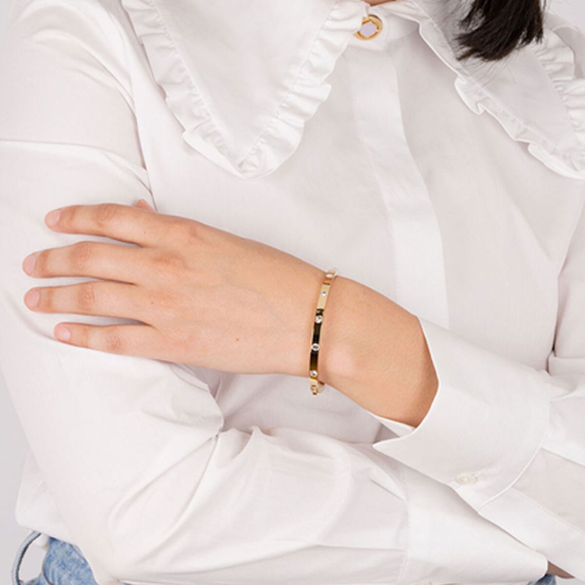 Gouden Lotus armband LS1846-2/2 om de pols, gedragen door een vrouw in een witte blouse.
