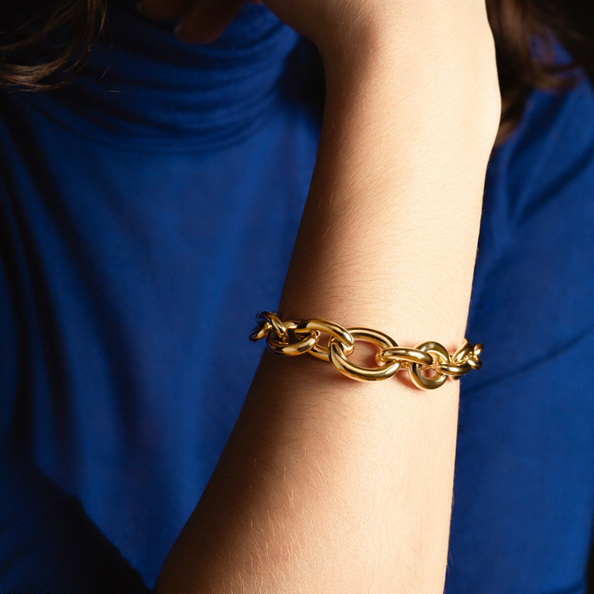 Detail van de gouden Lotus armband met elegante schakels, gedragen om een pols.