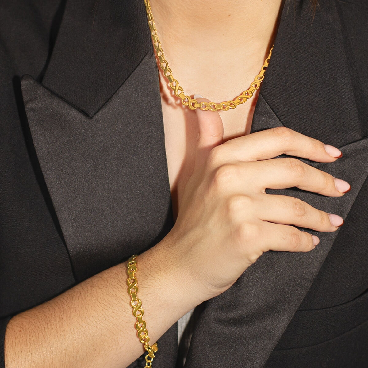 Close-up van de gouden Lotus ketting met elegant ontwerp, gedragen op een zwarte blazer.