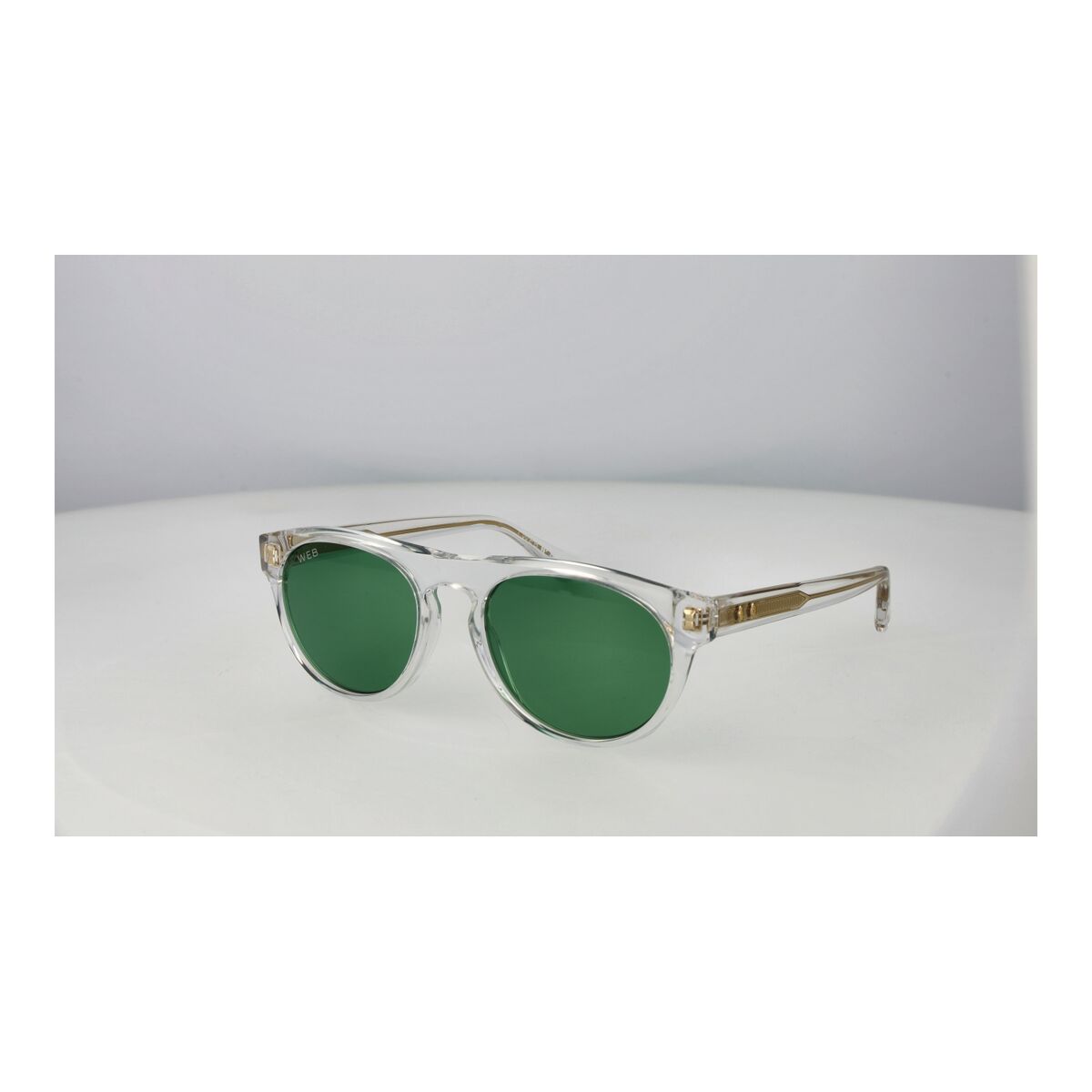 Detail van de Web Eyewear zonnebril met groene glazen en een transparant montuur.
