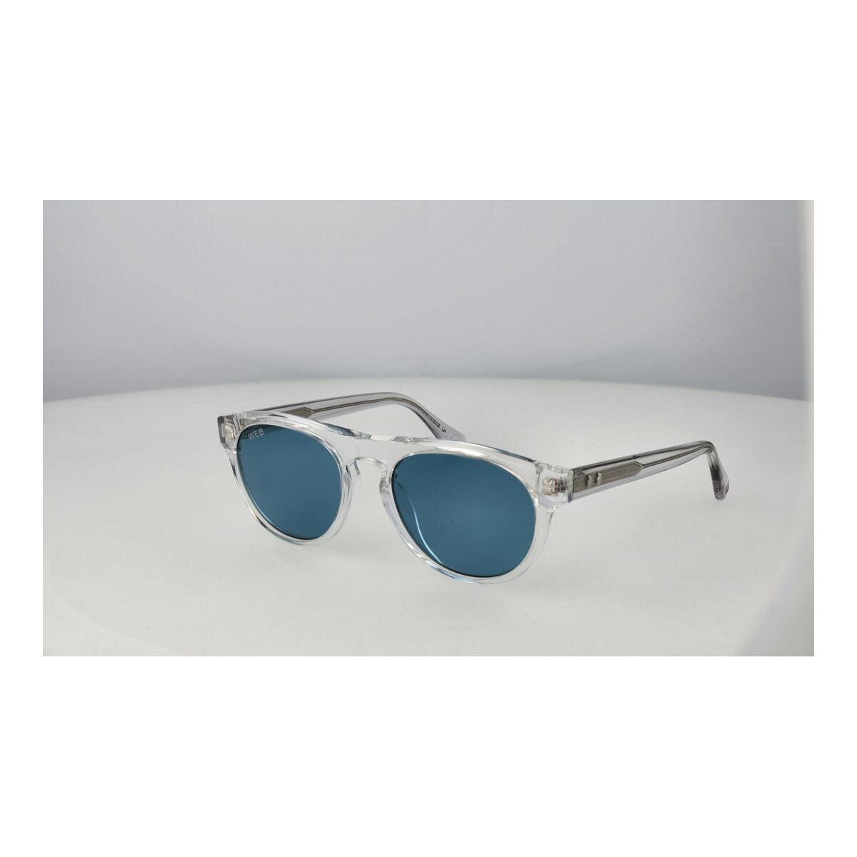Zijaanzicht van de Web Eyewear zonnebril met blauwe lenzen en transparante montuur.