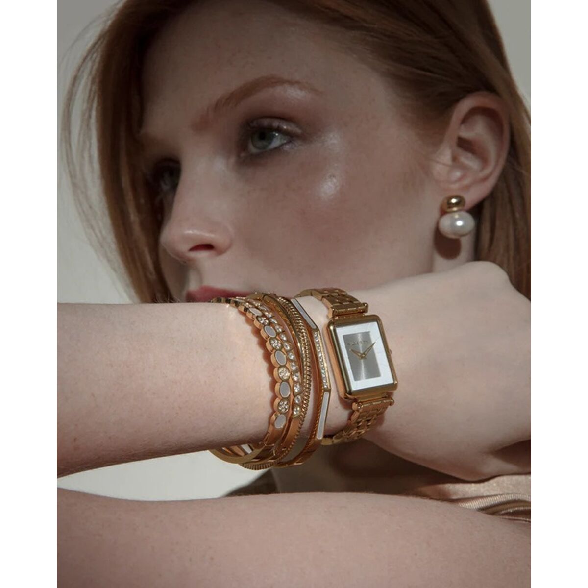 Detail van de Viceroy gouden armband gedragen met andere sieraden op een pols.