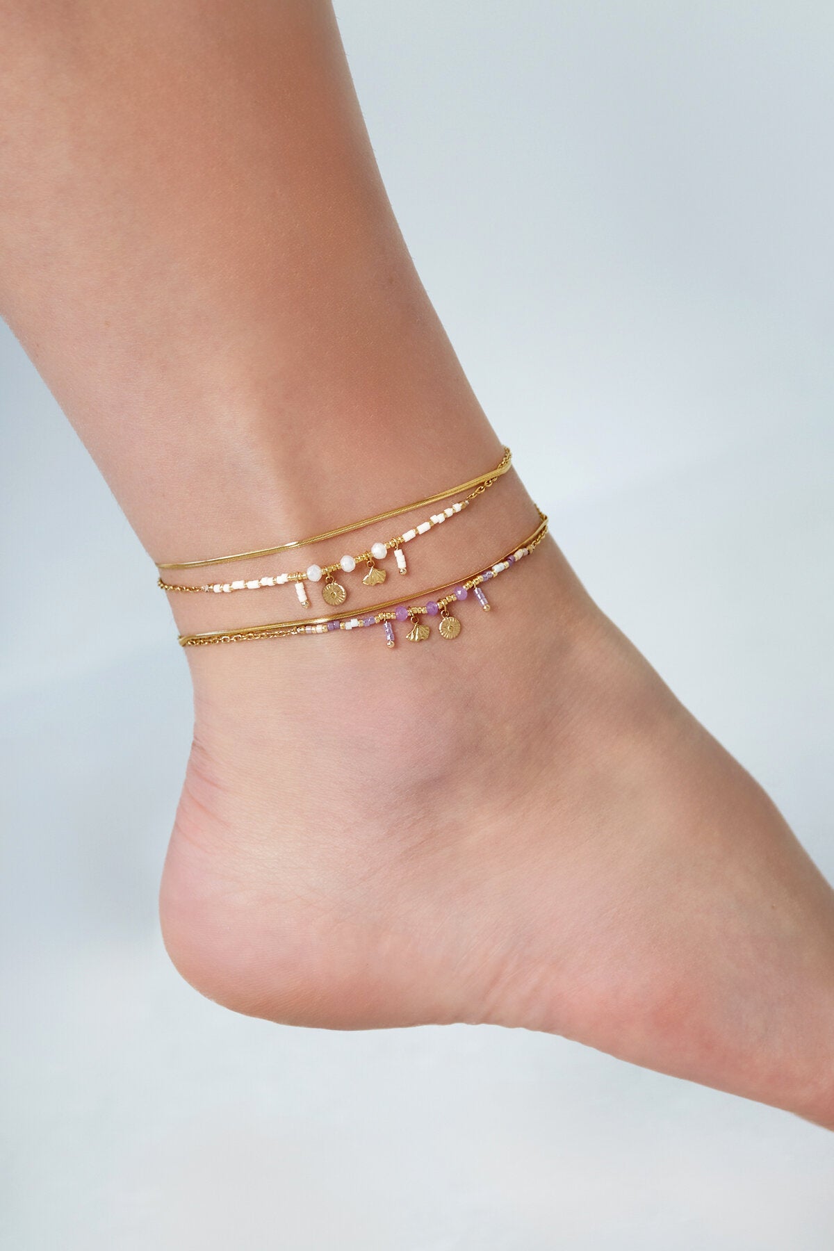 Detail van de Classy Vibe enkelband met gouden schakels en kleurrijke bedels aan een enkel.