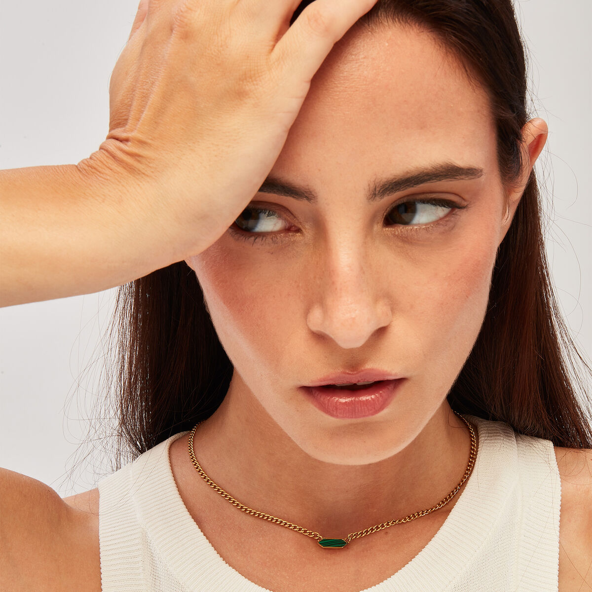 Detail van de gouden Breil ketting met een groene edelsteen, gedragen door een model.