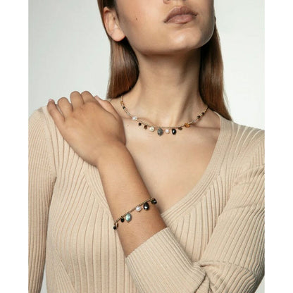 Detail van de Viceroy gouden armband, gedragen om de pols van een vrouw in een beige top.