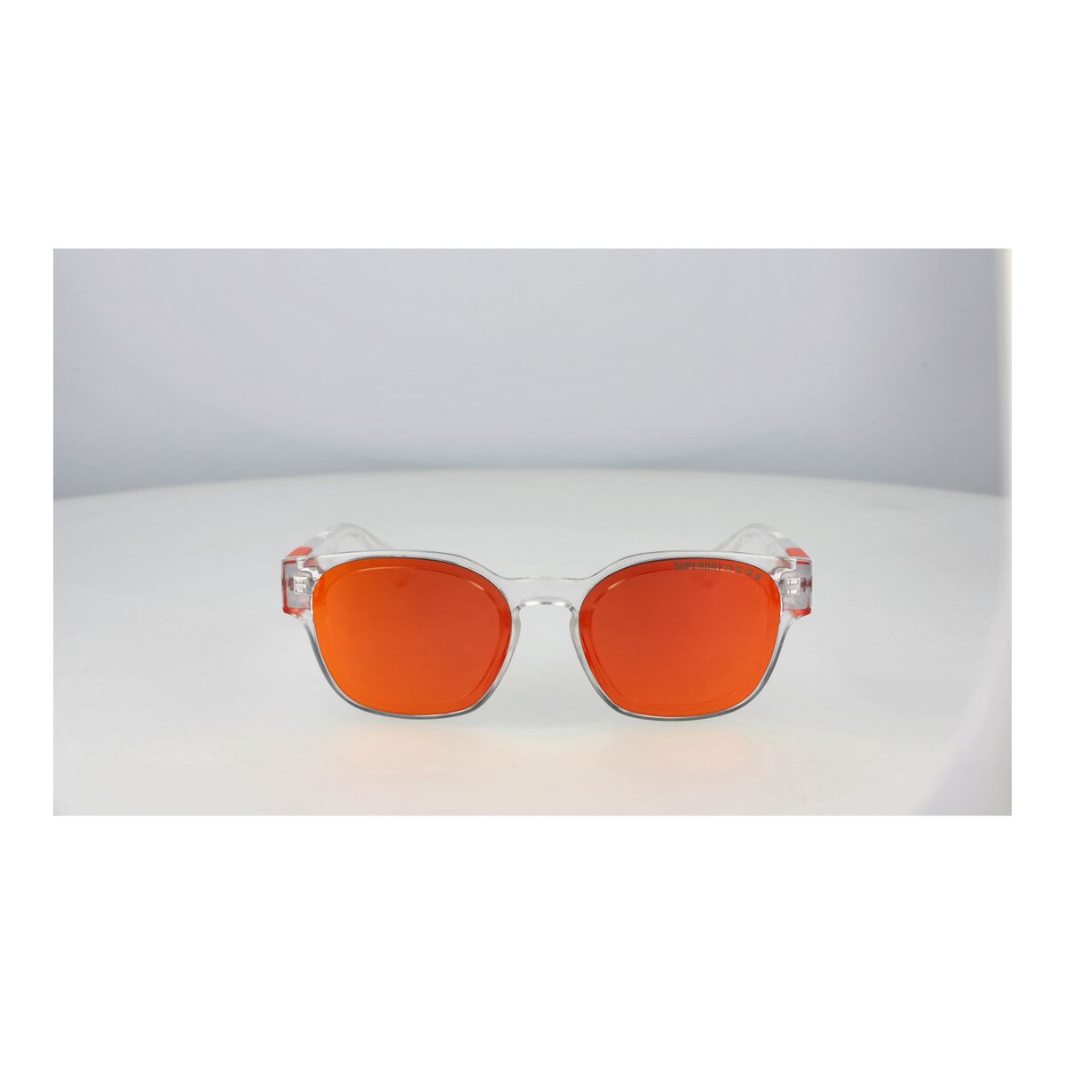 Zijaanzicht van de Superdry SDS XMONO zonnebril met oranje lenzen en transparante montuur.