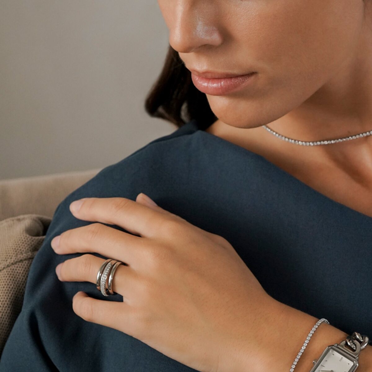 Zilverkleurige One Jewels ring op de hand van een vrouw, elegant gecombineerd met andere sieraden.