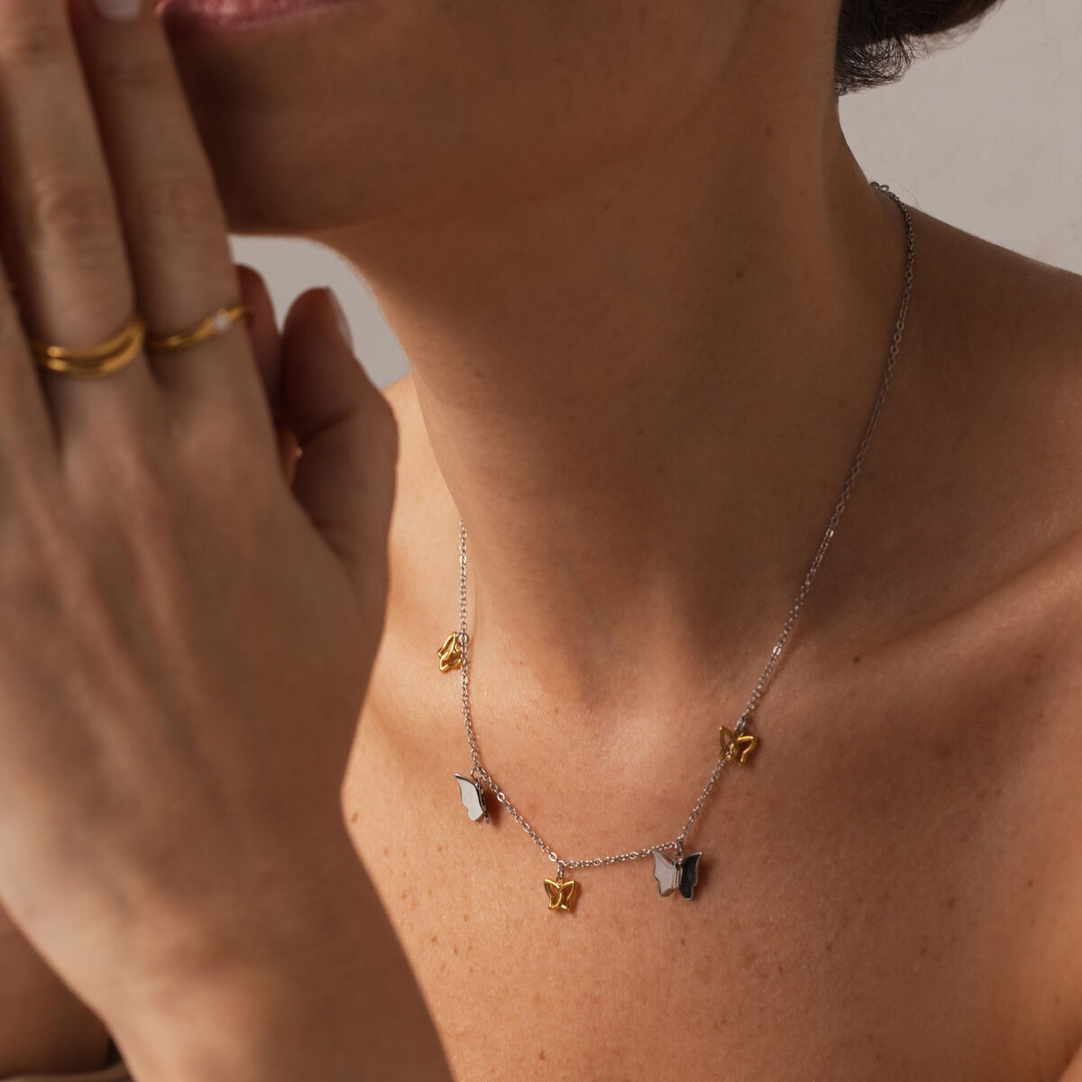 Detail van de zilverkleurige One Jewels ketting met gouden hartjes en een vrouwelijk model.
