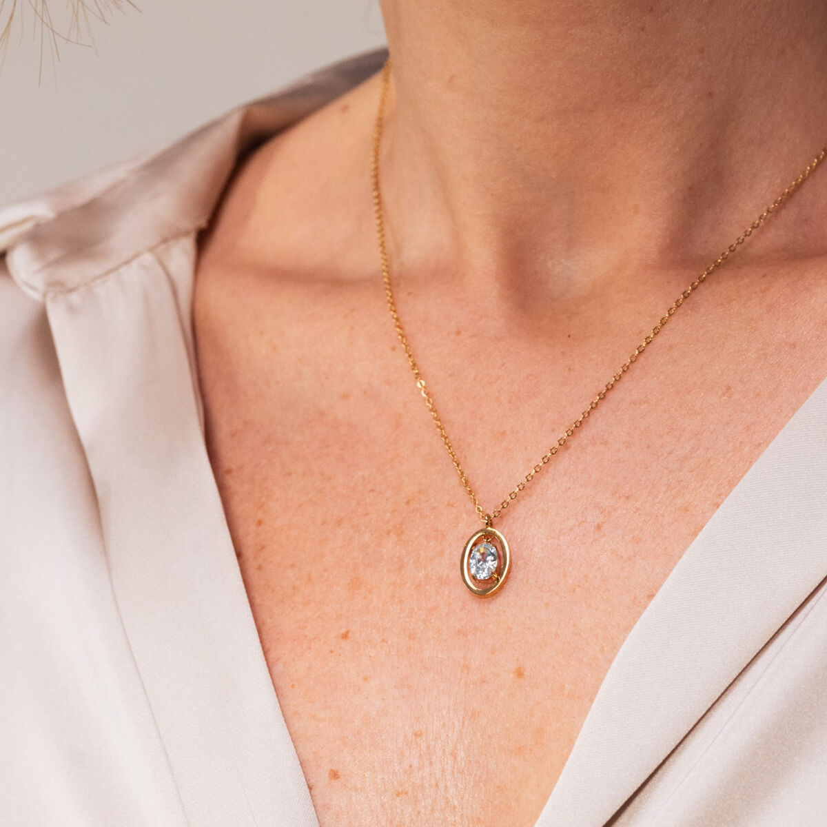 Close-up van de One Jewels gouden ketting met een elegante hanger, gedragen door een vrouw.