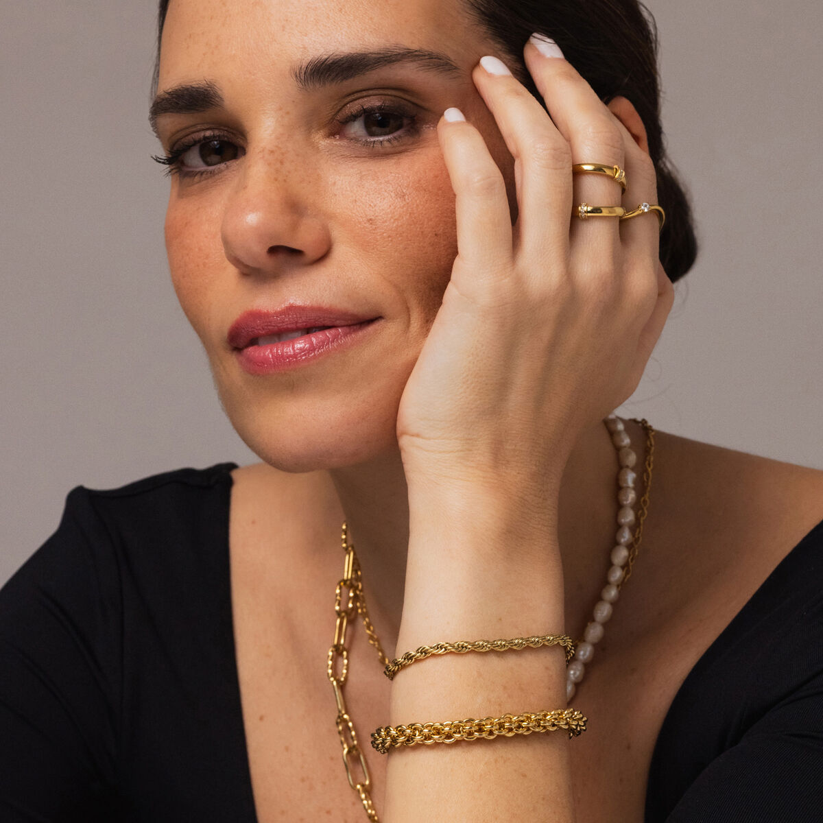Detail van de One Jewels gouden armband gedragen door een vrouw met elegante accessoires.