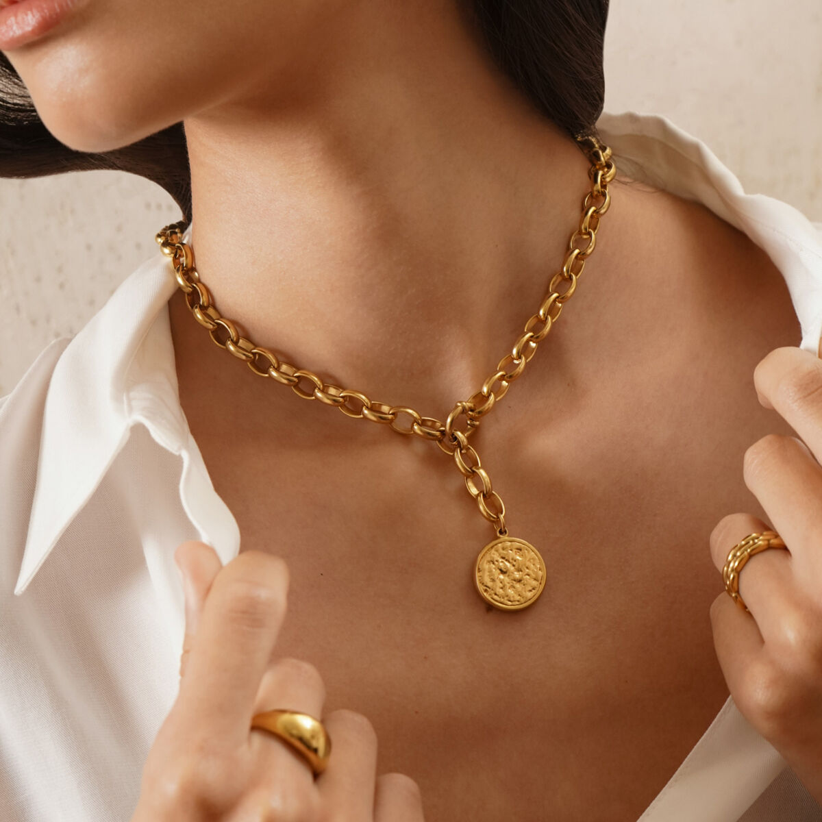 Detail van de gouden One Jewels ketting met een ronde hanger, gedragen om de hals.