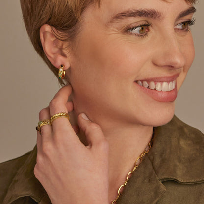 Close-up van een vrouw met een gouden One Jewels ring en oorbellen, lachend en stijlvol.