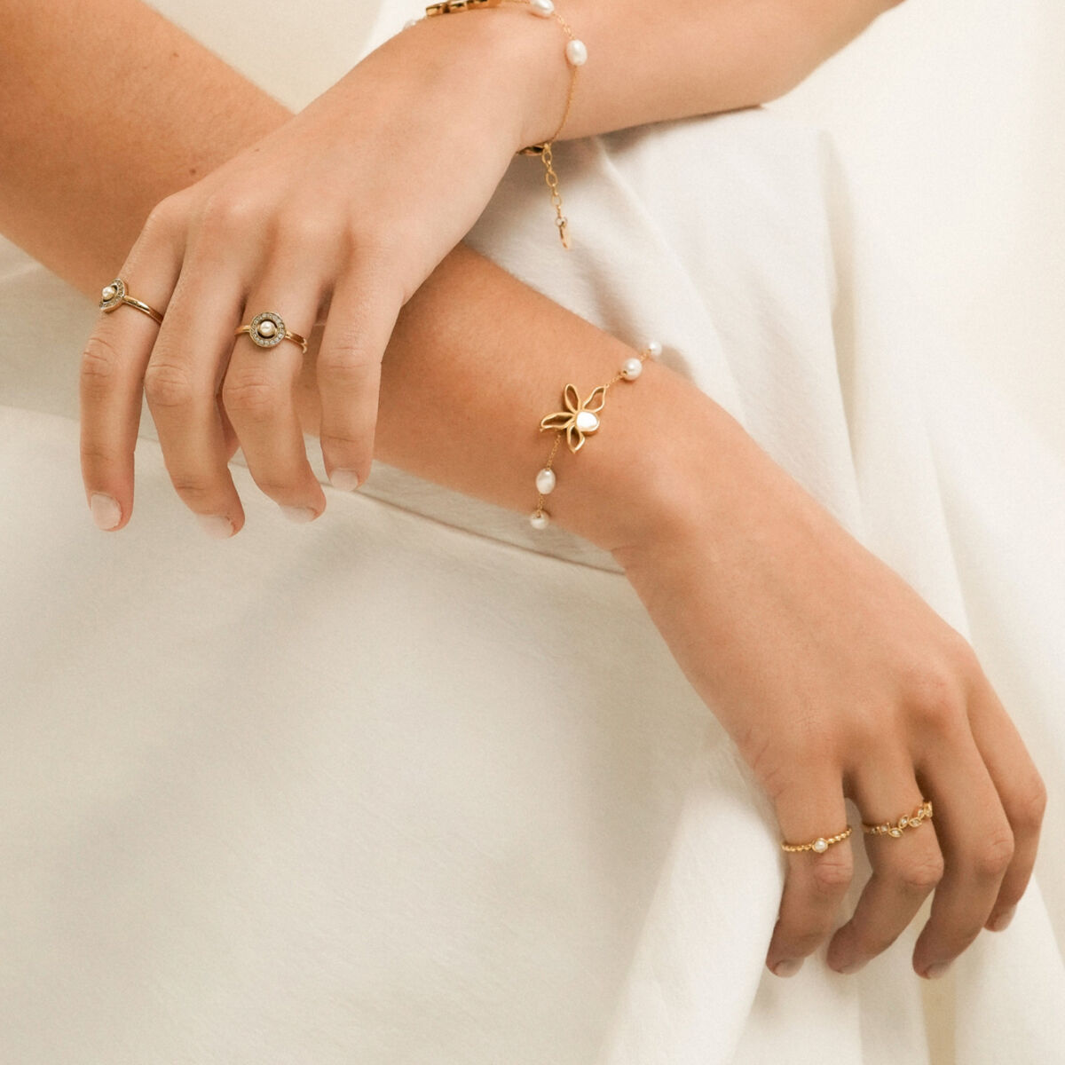 Detail van de One Jewels gouden armband met elegante bloem en parels om een pols.
