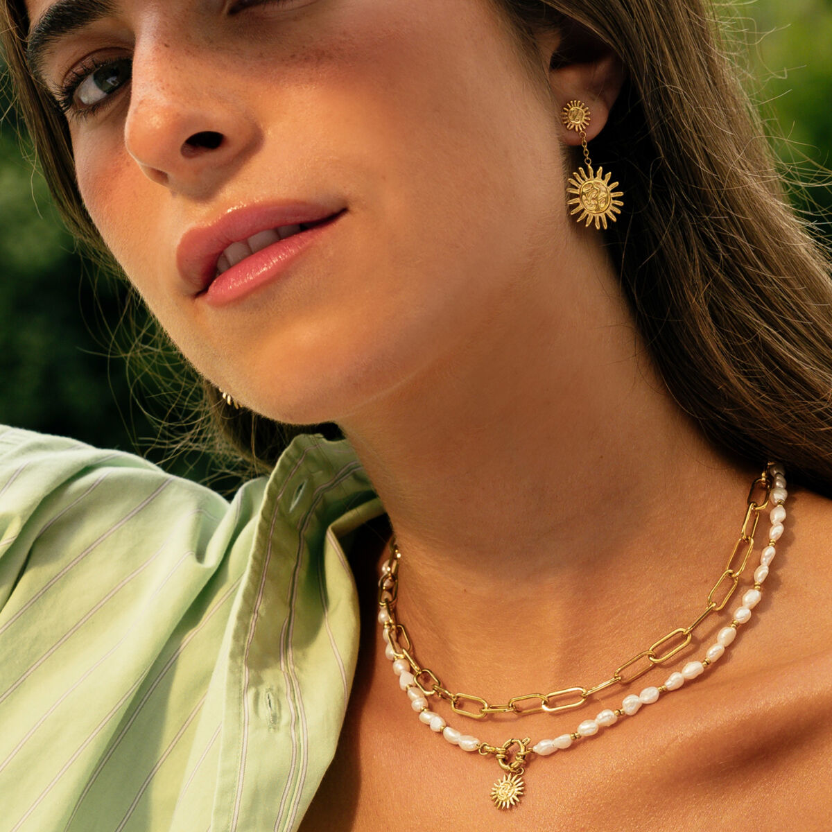 Detail van de gouden One Jewels ketting met elegante schakels en een zonnenhanger.