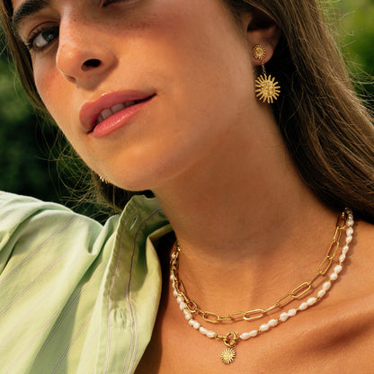 Detail van de gouden One Jewels ketting met elegante schakels en een zonnenhanger.