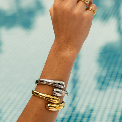 Zilverkleurige One Jewels armband gedragen om een hand, met een glanzend en elegant ontwerp.