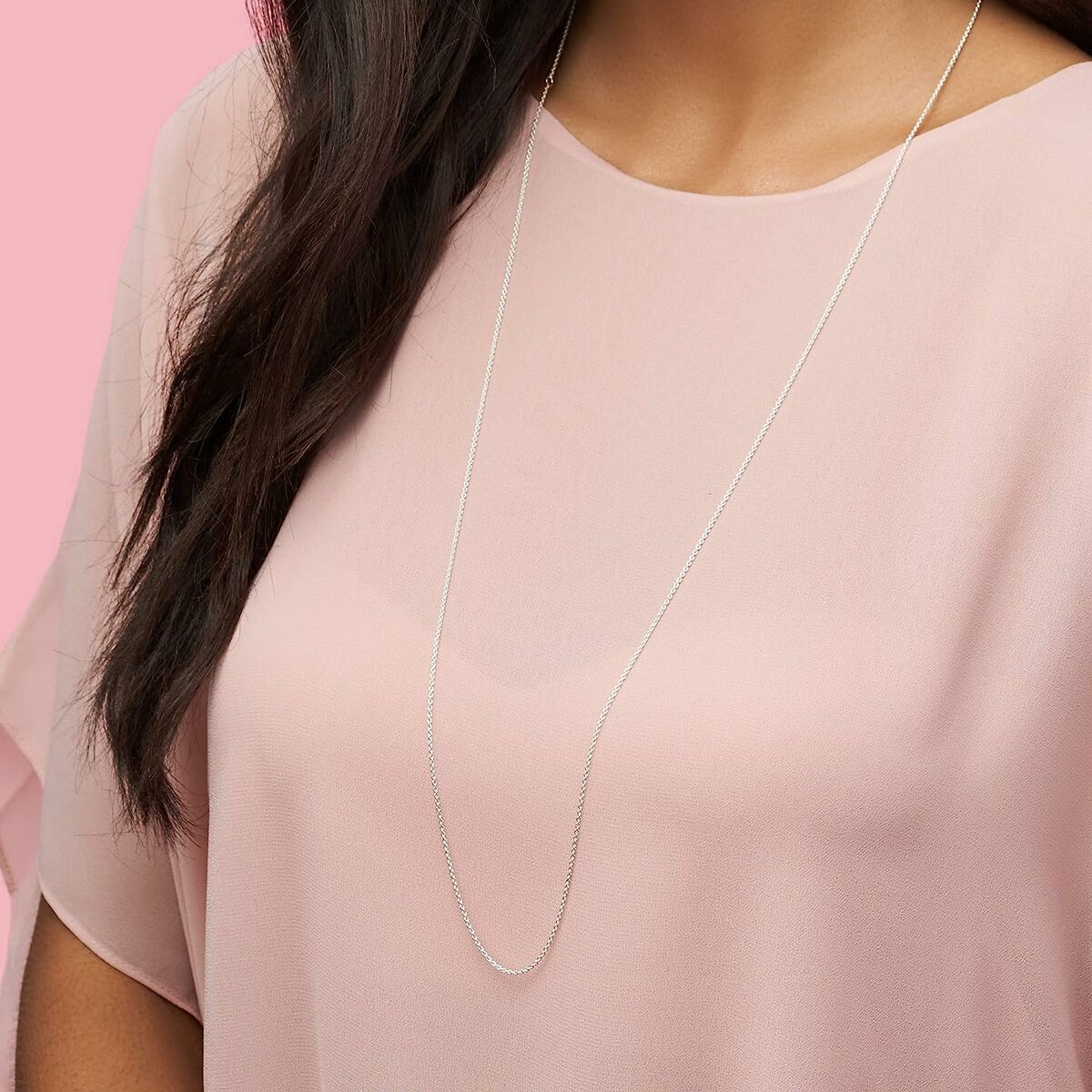 Zilverkleurige Pandora ketting elegant gedragen boven een roze blouse.