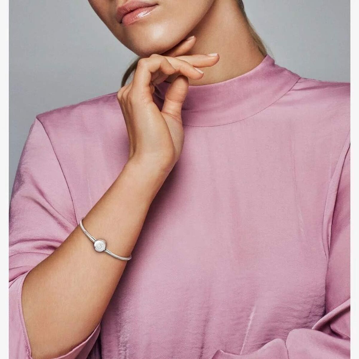 Elegante Pandora Snake Chain armband van sterling zilver, gedragen door een vrouw in een roze top.