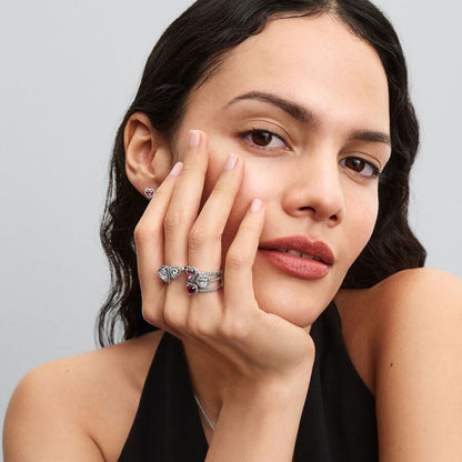 Roze zilverkleurige Pandora oorbellen elegant gedragen door een vrouw met hand aan haar gezicht.