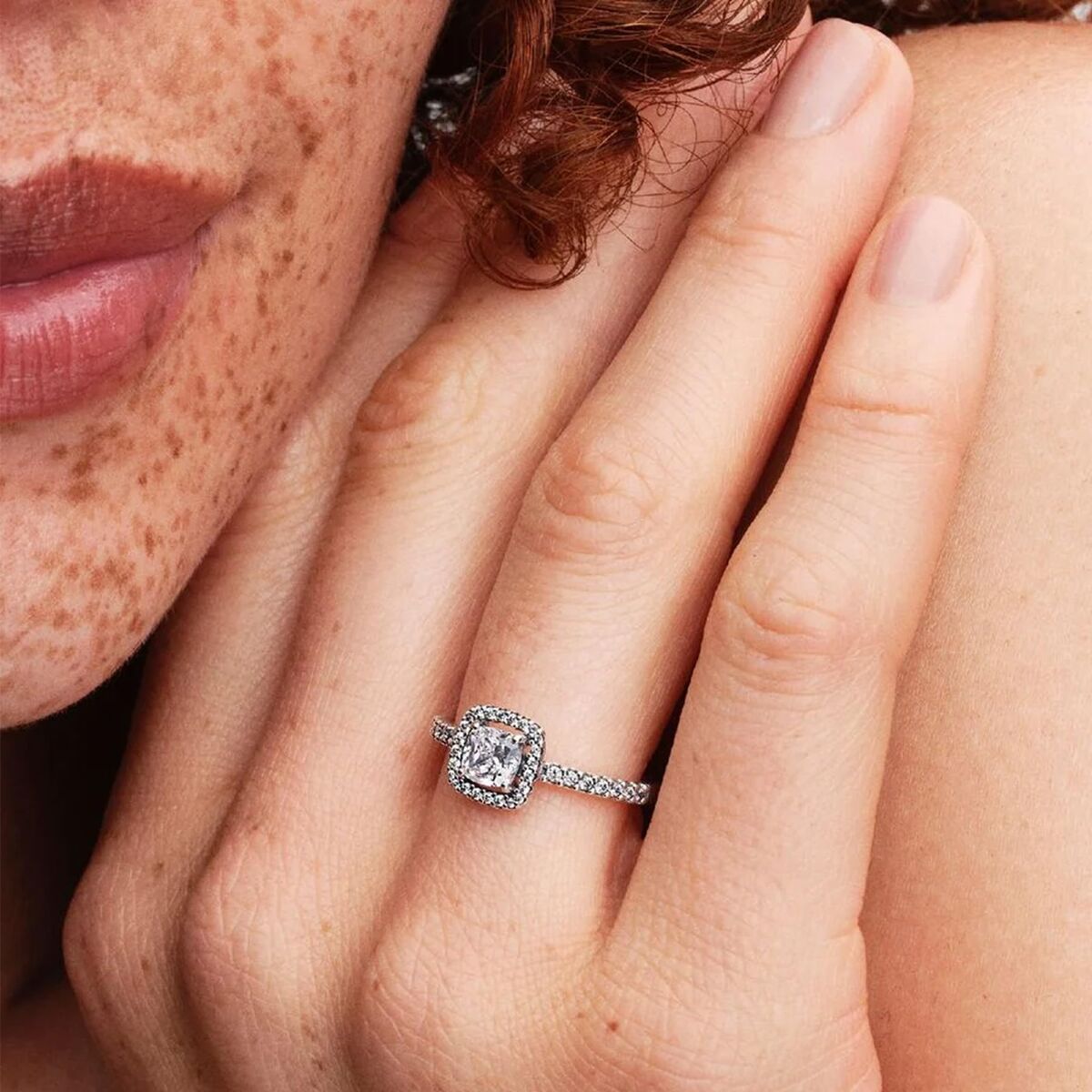 Detail van de Pandora ring met zilverkleurig ontwerp en sprankelende steen, gedragen op de hand.