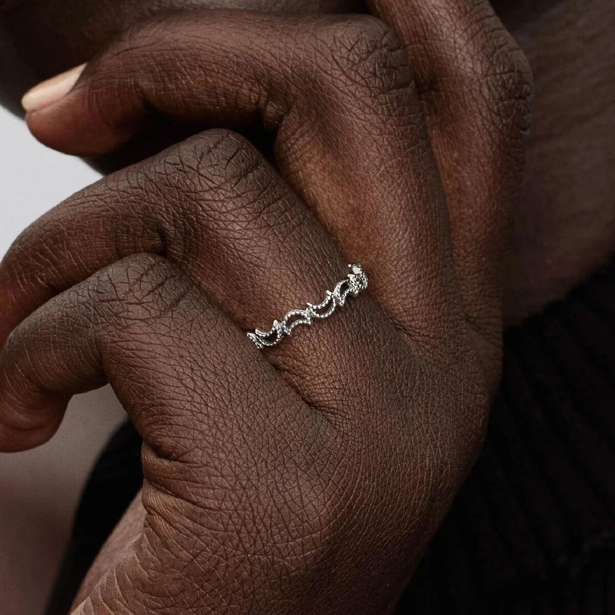 Detail van de zilverkleurige Pandora ring met golvende ontwerpen, gedragen op een hand.
