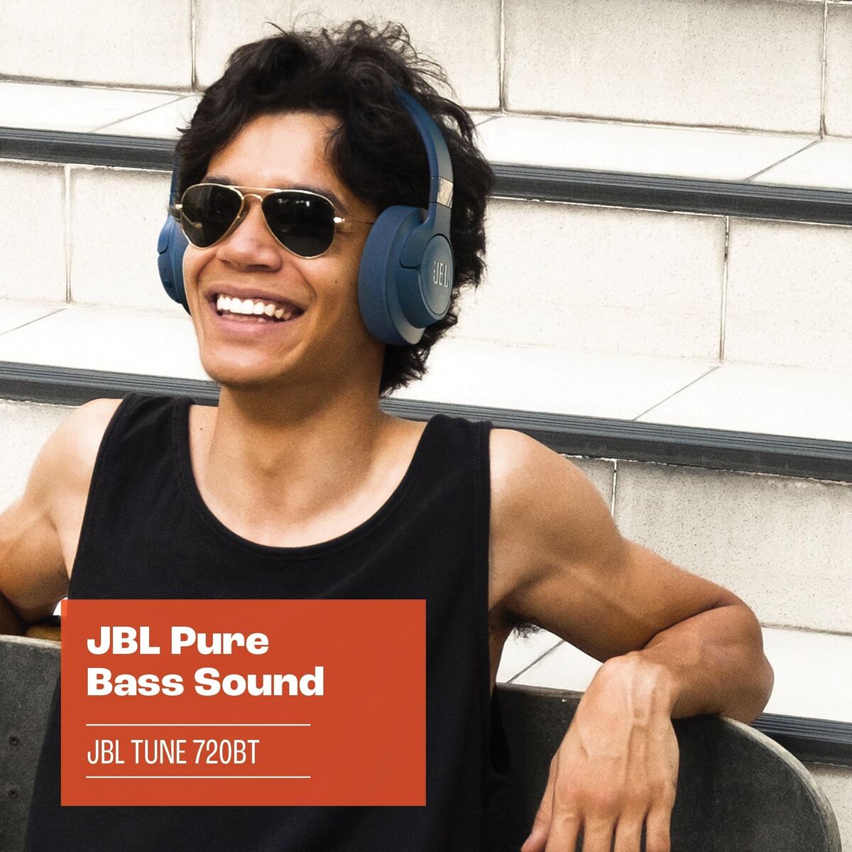 JBL oordopjes in gebruik door een lachende man met zonnebril, casual outfit.