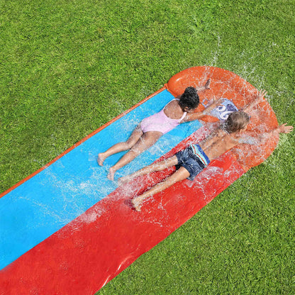 Kinderen glijden samen van de Bestway H2OGO Tsunami Splash Ramp waterglijbaan op gras.