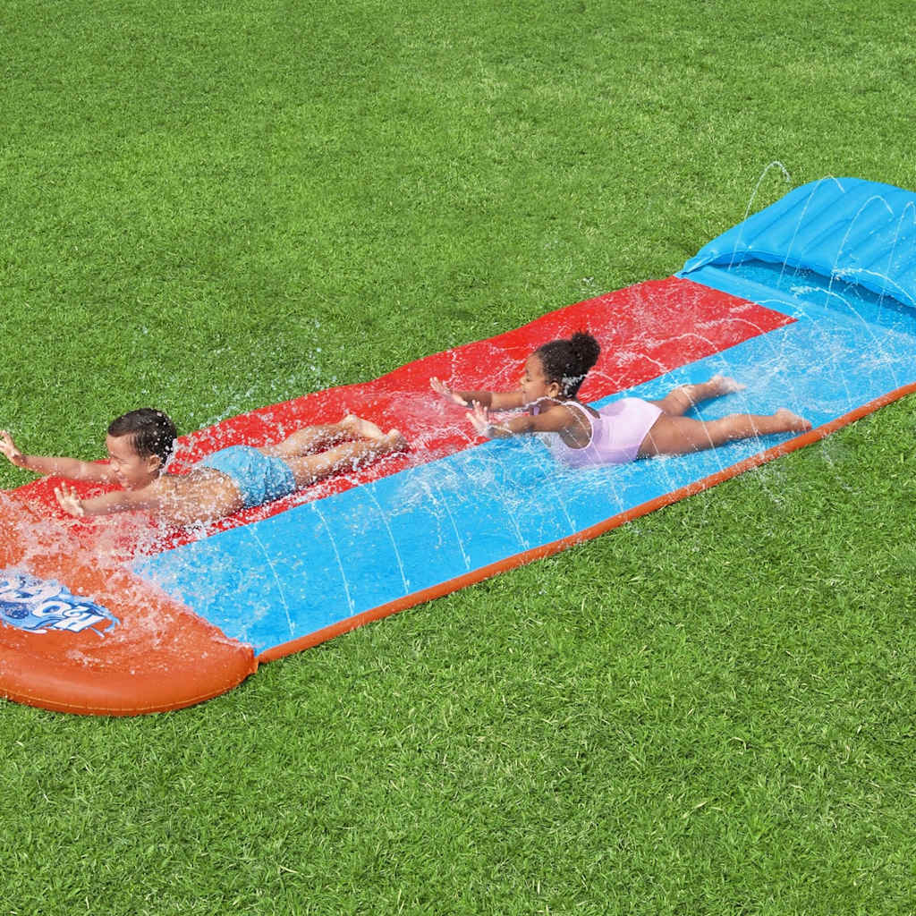 Kinderen glijden samen van de Bestway H2OGO Tsunami Splash Ramp op een groene grasmat.