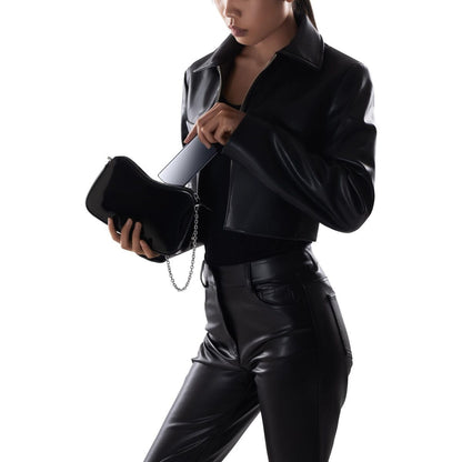 Zijaanzicht van een vrouw in leren outfit die een smartphone uit een zwarte tas haalt.