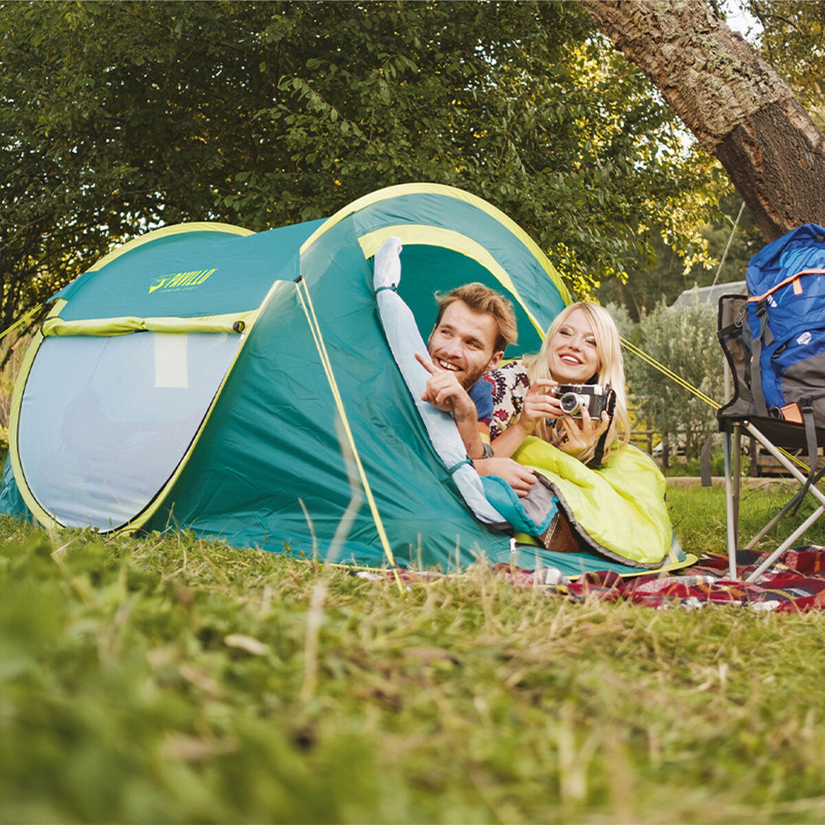 Groene Bestway kampeertent met twee mensen erin, genietend van de natuur.