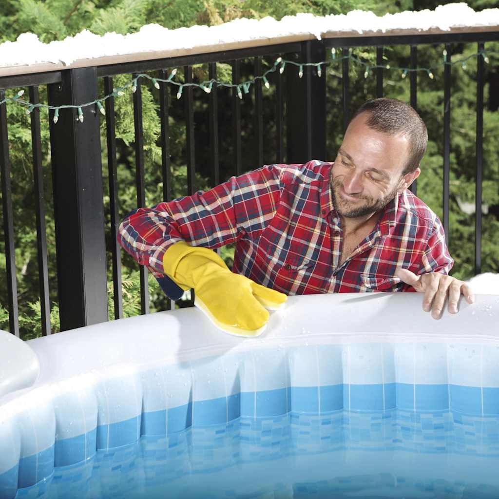 Man in een geruit shirt met gele handschoenen, die de Lay-Z-Spa schoonmaakt.