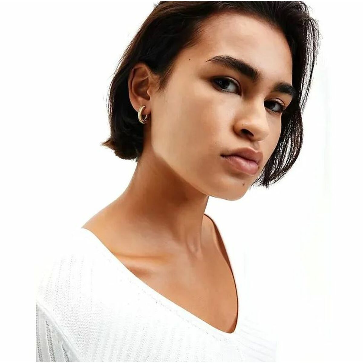 Zijaanzicht van een vrouw met Calvin Klein roestvrijstalen oorbellen in een stijlvolle outfit.