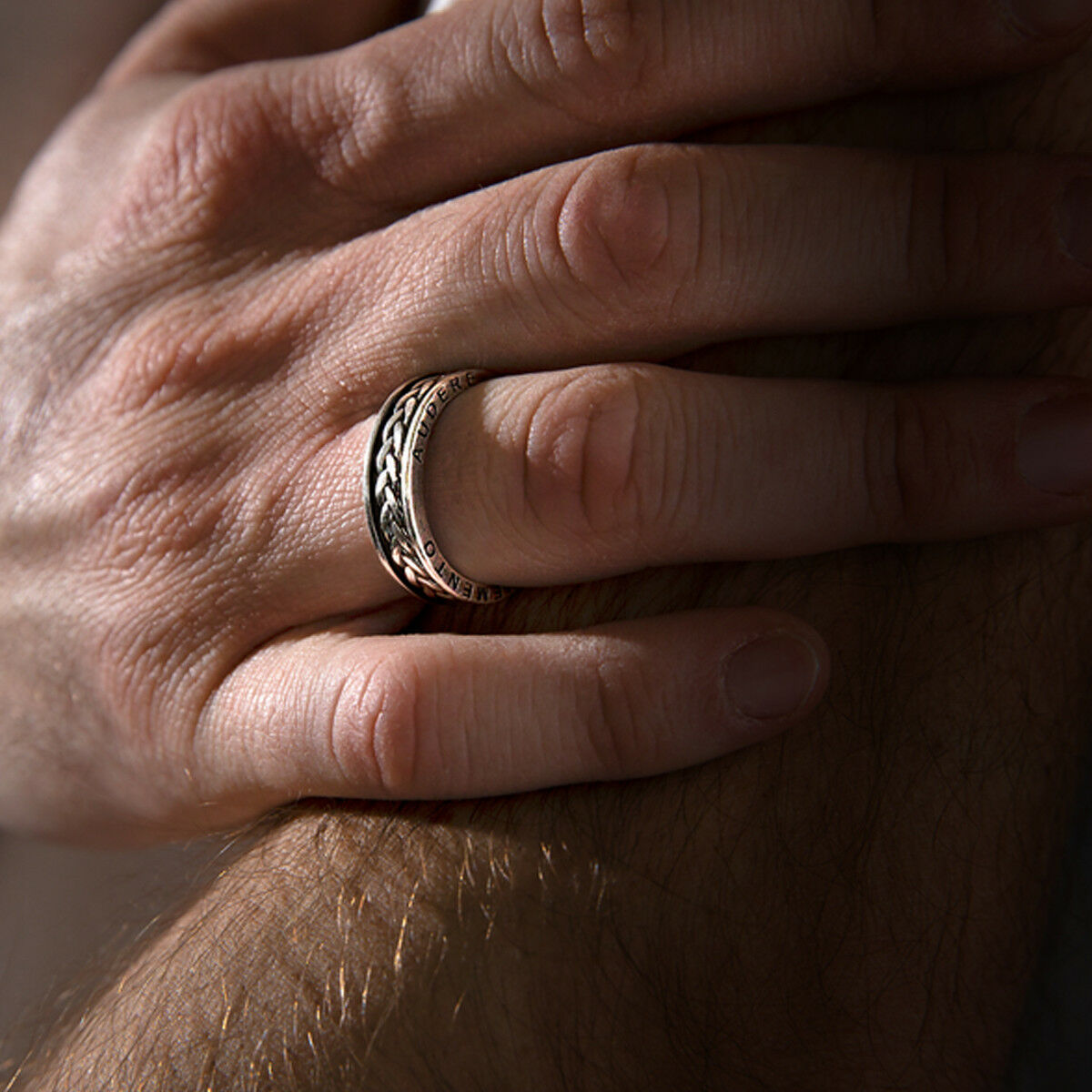 Zilverkleurige Albert M. ring met gedetailleerde band, gedragen op een hand.