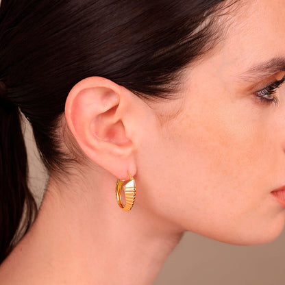 Detail van de gouden Etrusca oorbellen in elegant design, gedragen aan het oor.