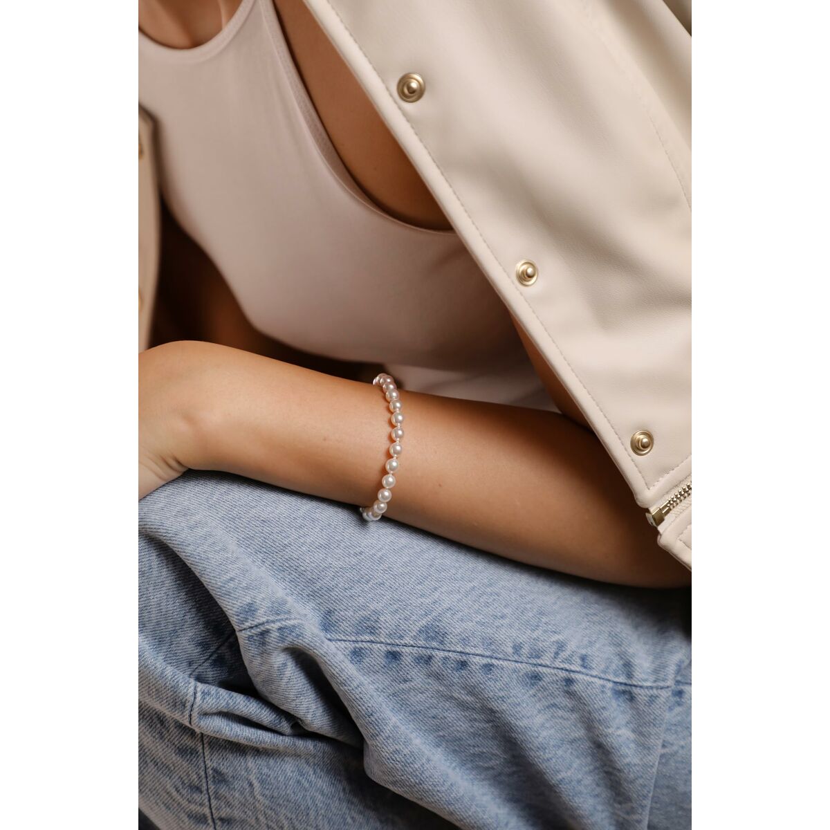 Detail van de zilverkleurige Majorica armband om de pols van een model in casual outfit.
