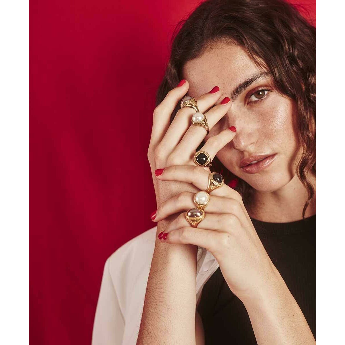 Detail van een vrouw die meerdere Majorica ringen met gouden afwerking draagt.