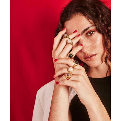 Detail van een vrouw die meerdere Majorica ringen met gouden afwerking draagt.