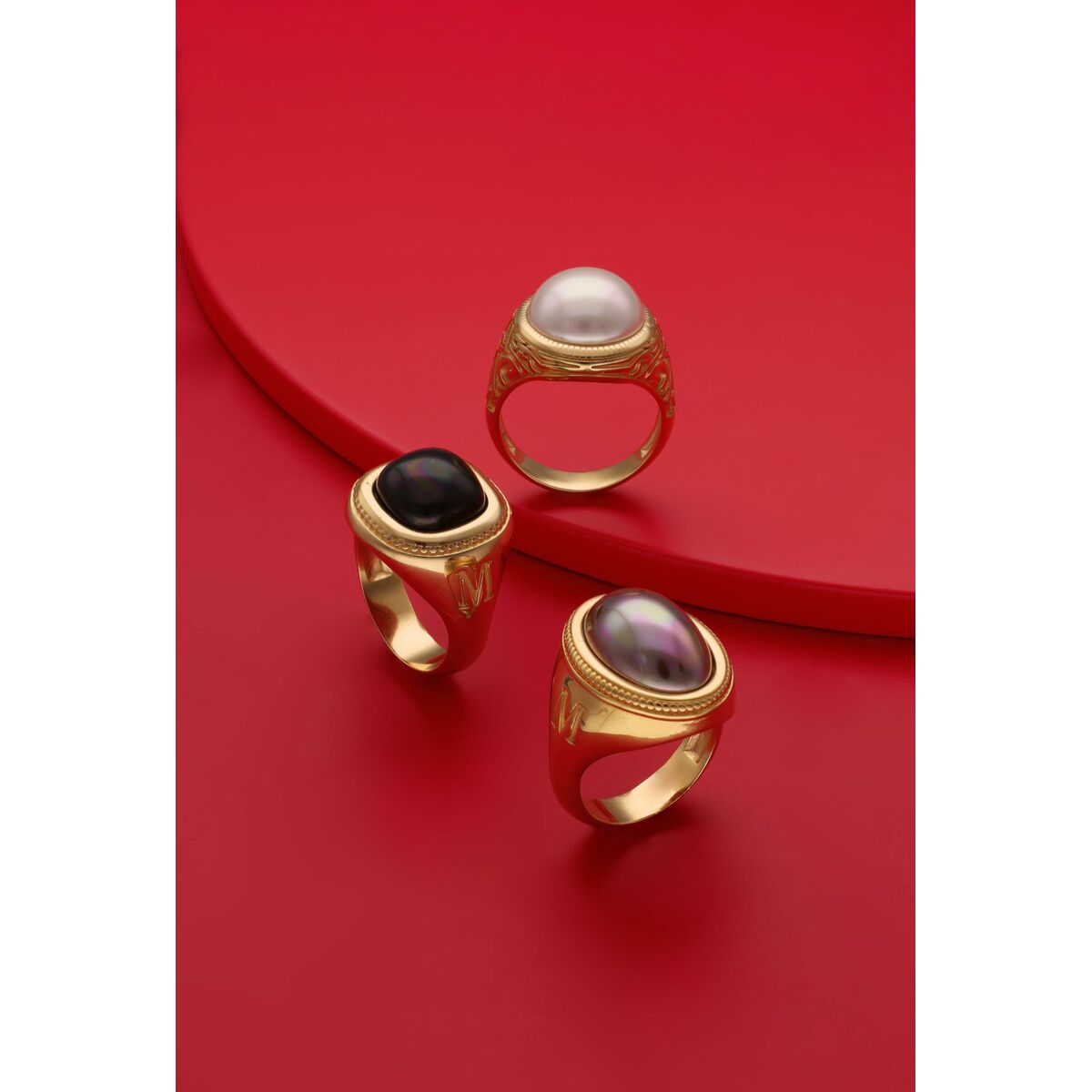 Detail van de Majorica ring met gouden afwerking en parel, zijaanzicht op rode achtergrond.