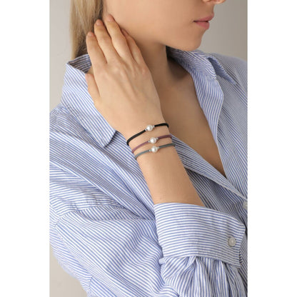 Detail van de Majorica armband met parels, gedragen door een vrouw in een gestreepte blouse.