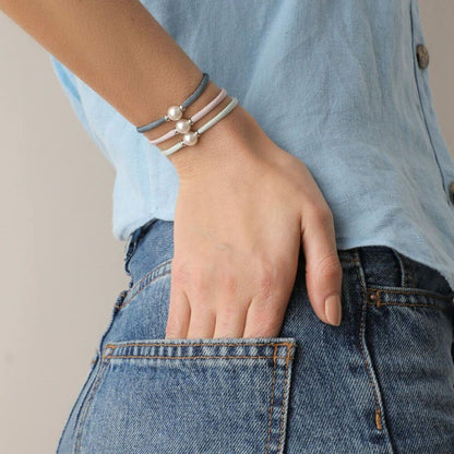Detail van de Majorica armband met parels, gedragen om een pols met een spijkerbroek.