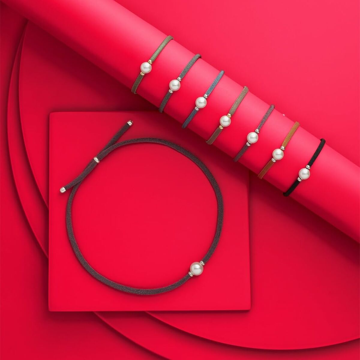 Detail van de Majorica armband met elegante parel, gepresenteerd op een felrode achtergrond.