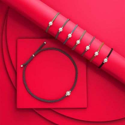 Detail van de Majorica armband met elegante parel, gepresenteerd op een felrode achtergrond.
