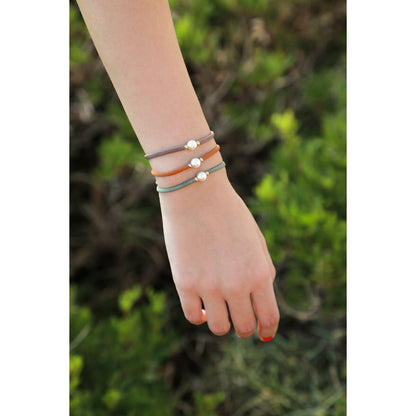 Detail van de Majorica armband met parels, gedragen om een hand in een groene omgeving.