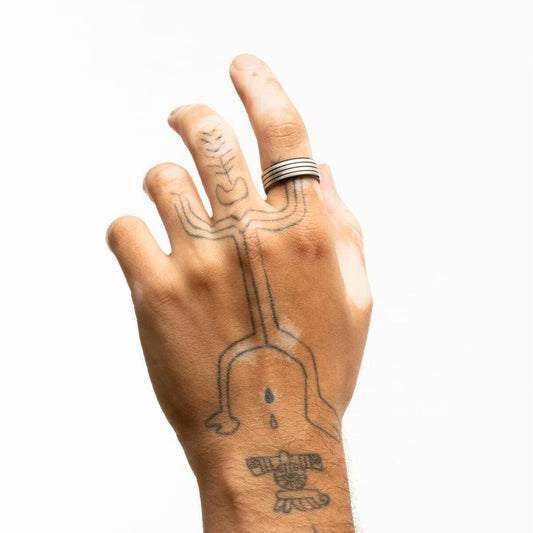 Zilverkleurige Lotus ring maat 20, elegant gedragen op een hand met tatoeages.